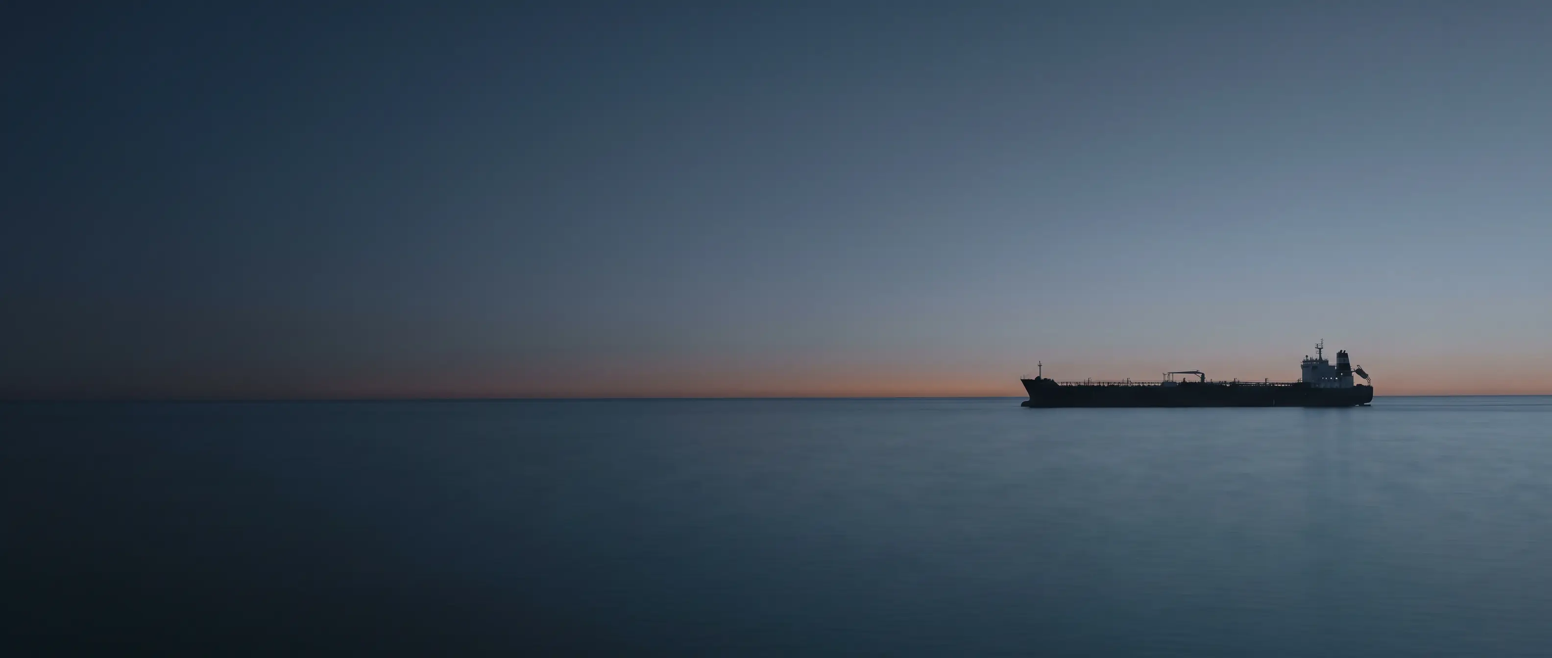 Product tanker silhouette on the horizon at dusk