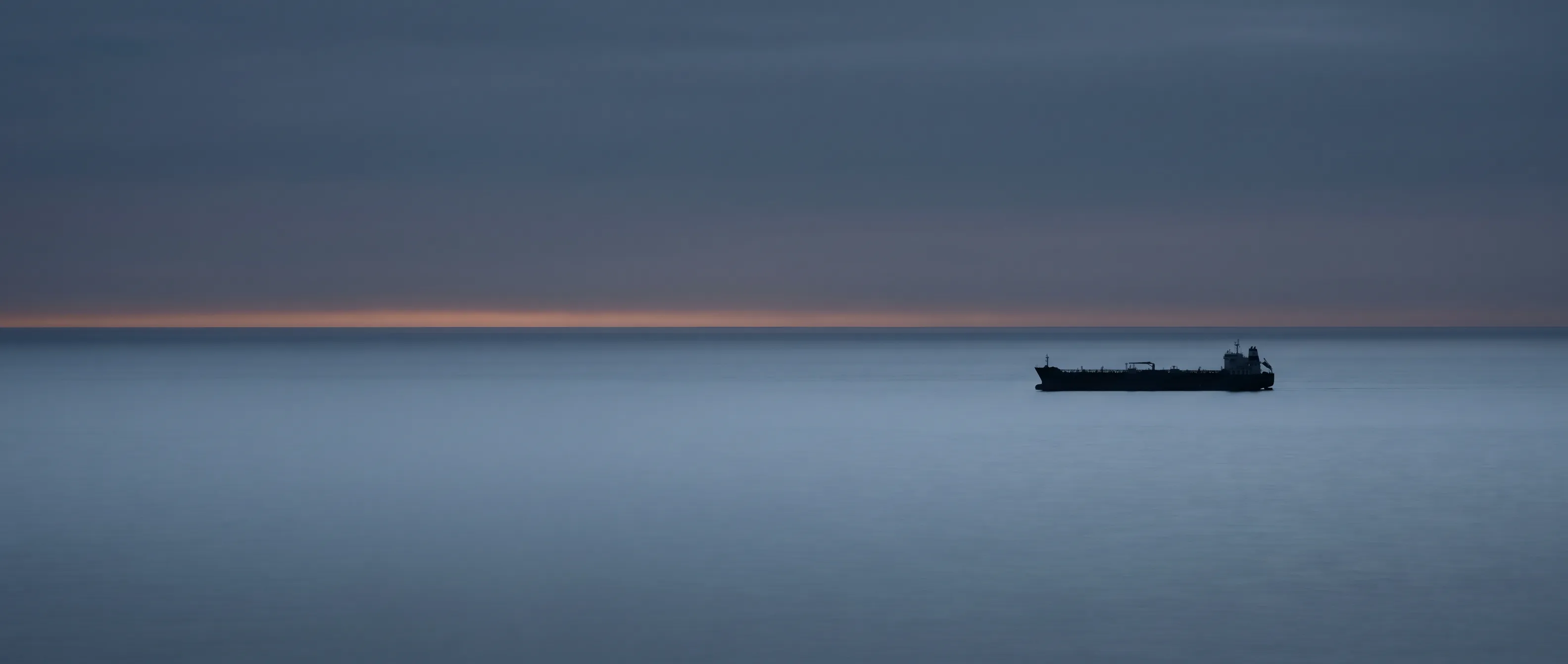 Silhouette of a tanker on the horizon at dusk